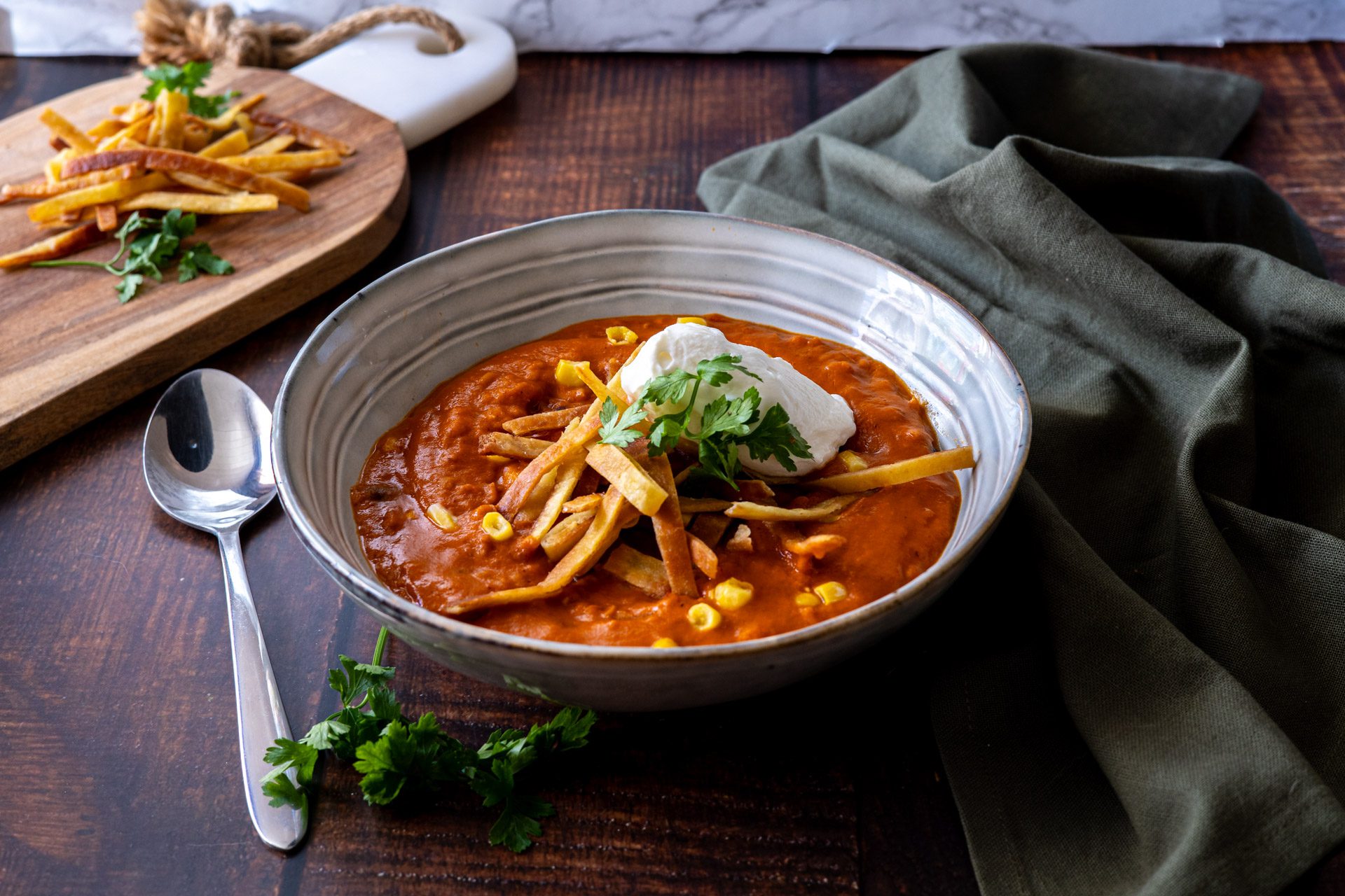 skål med linssoppa toppad med tortillastrips och yoghurt